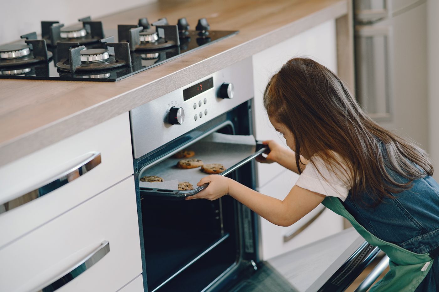 Woman handling a baking dish beside an open oven