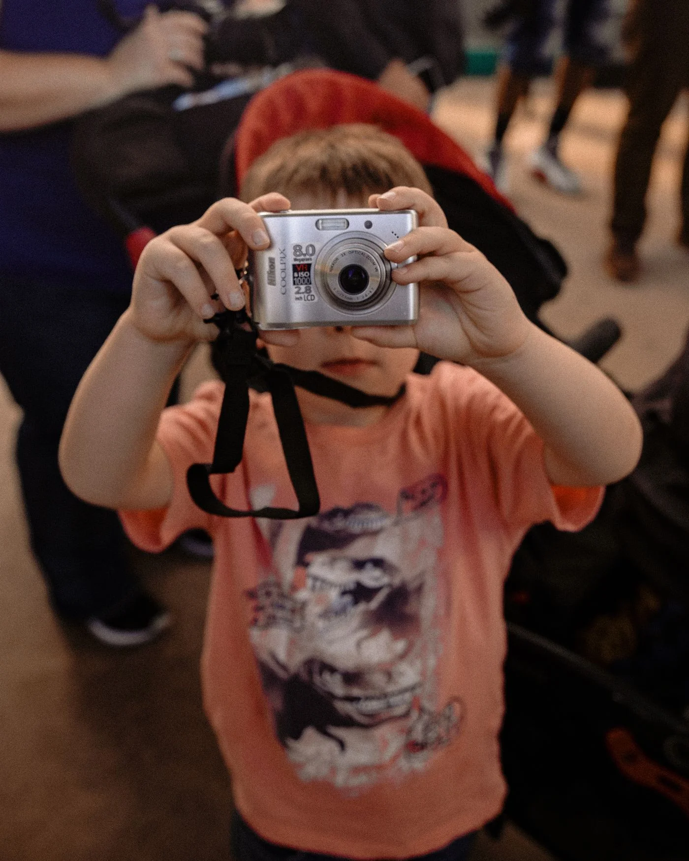 A child holding a digital camera in an urban setting.