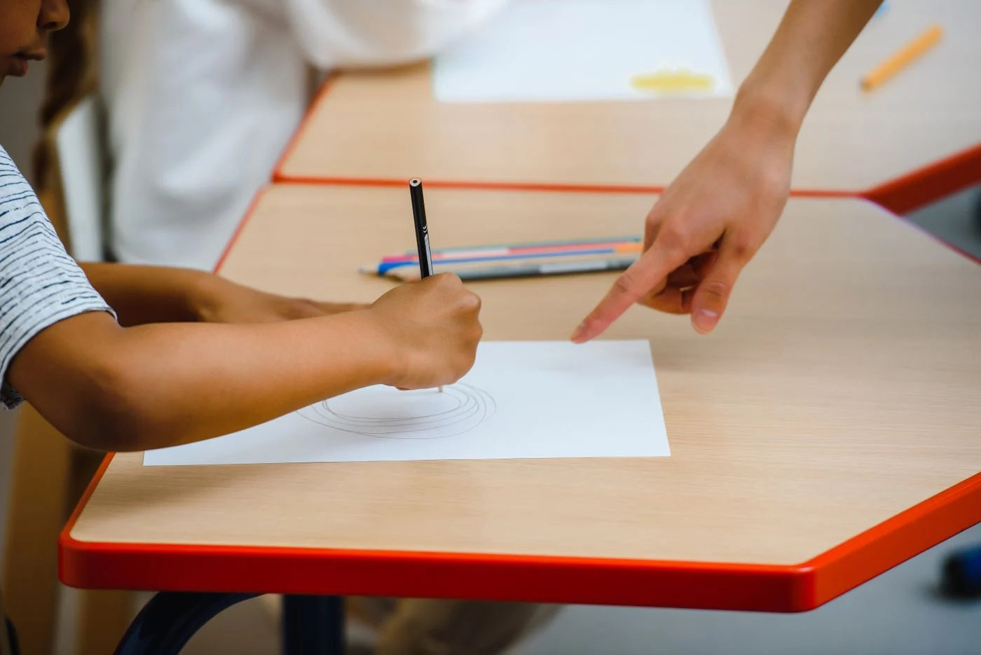 Child drawing at a table with adult guidance