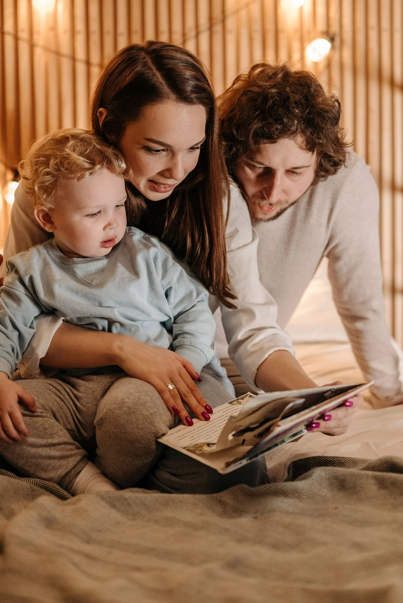 Parents and a child reading a book together indoors