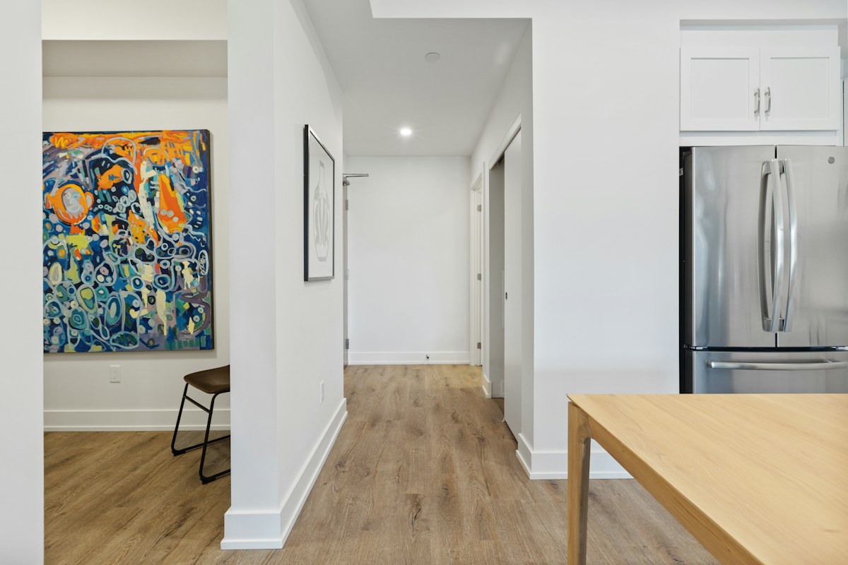 A pale kitchen with wooden island, refrigerator and framed artwork